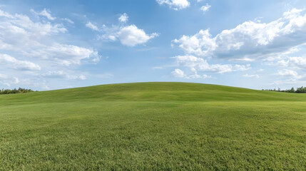 Fototapeta premium Lush green hill under bright blue sky with fluffy clouds, creating serene landscape