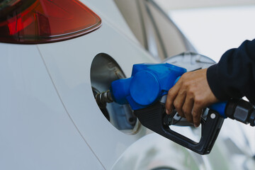 Close-up of gas station attendant's hands and fuel nozzle refueling.