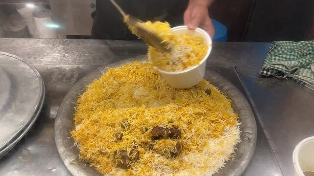 Serving of Kolkata style mutton biryani to customers.