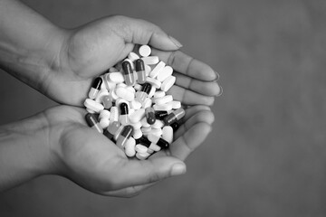 black and white image of hands holding pills