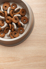 Dry dog food in a slow feeder bowl placed on a wooden surface