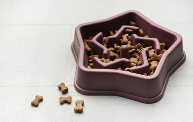 Slow feeder dog bowl filled with dry pet food preventing fast eating
