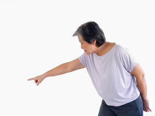 Asian elder woman pointing fingers to empty space, choice or deciding, suspicious with warning, guilty or blame, standing isolated over white background wall.