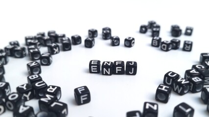 Scattered black plastic cubes, focus on the letters ENFJ in the center. The foreground and...