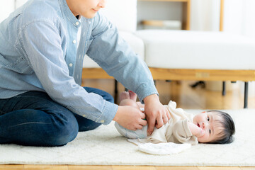  赤ちゃんの紙オムツを交換するパパ