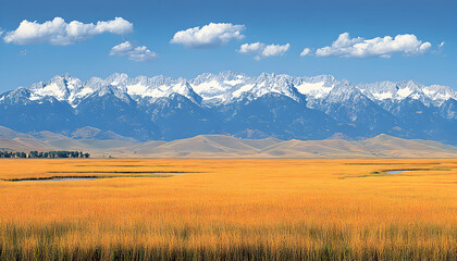 Fototapeta premium Stunning panoramic view of a golden prairie stretching towards a majestic snow-capped mountain range under a vibrant blue sky.
