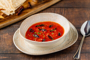Spicy Mexican tomato soup with dried chili peppers in a rustic bowl