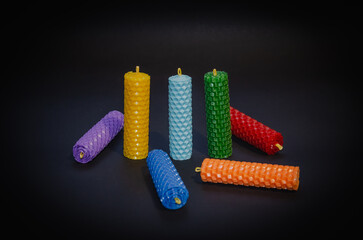 Candles of different colors on a black background, chakra candles