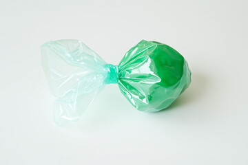 A Single Green Mint Candy Resting on a Plain White Surface.