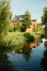 Obraz premium Modern houses reflecting in canal water with lush green vegetation