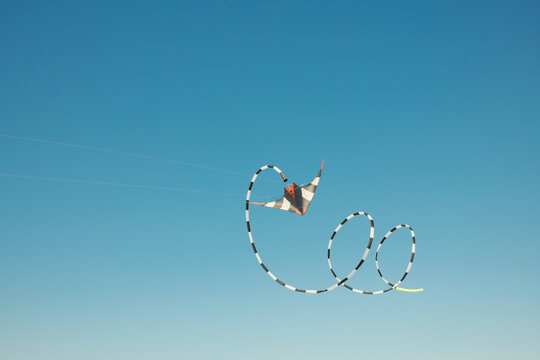 Colorful kite flying in the blue sky with spiral tail