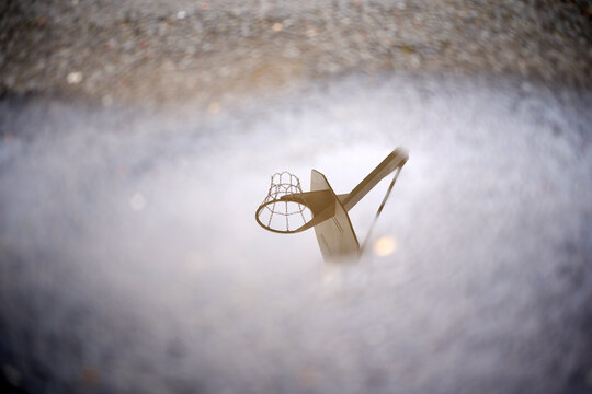 Basketball hoop reflecting in a puddle after the rain