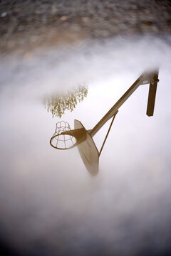 Basketball hoop reflecting in puddle after rain shower
