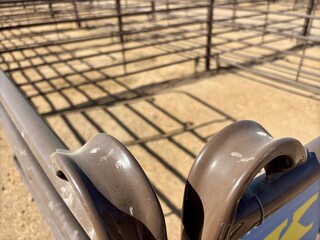 Close-up of a livestock gate latch with fencing shadows on the ground