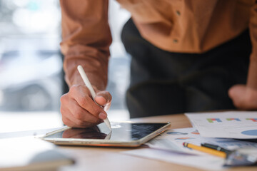Businessman analyzing and signing documents using a digital tablet