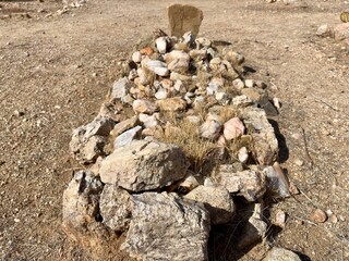 Close-up of a rustic desert grave marked by piled stones and dirt