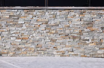 Fence made of faux stone veneer wall and black metal paneling on top . Concrete flooring....