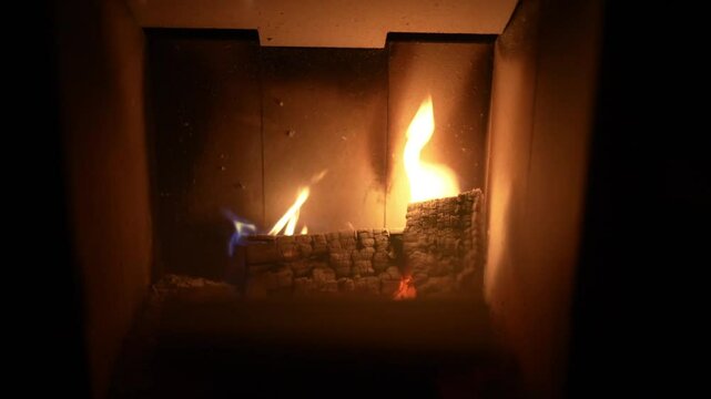 Closeup view of firewood burning inside home firebox with dancing flames in slow motion.