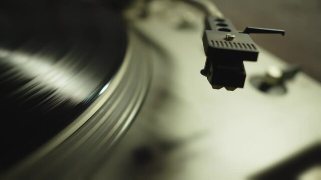 Close up of record player arm lifting from spinning vinyl on turntable