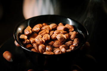 Delicious hazelnuts arranged in a black bowl with a dark background, showcasing natural texture and color contrasts