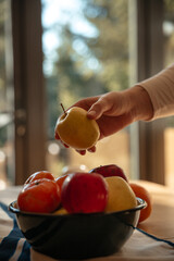 Hand holding organic healthy apple, bowl of fruit