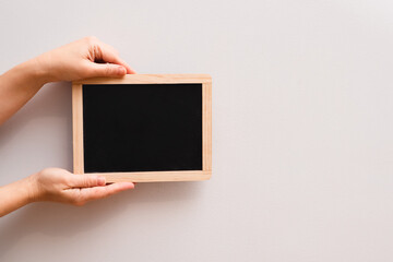 Woman's hand showing chalkboard. Place for writing text on a blackboard. Hands holding a empty black board on white