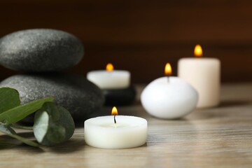 Beautiful composition with burning wax candles, stones and eucalyptus on the tablе