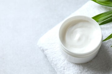 Cosmetic jar with moisturizing cream. Natural cosmetic products on the towel, top view