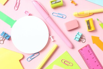 Flat lay with school stationery with white paper card on pink background, top view