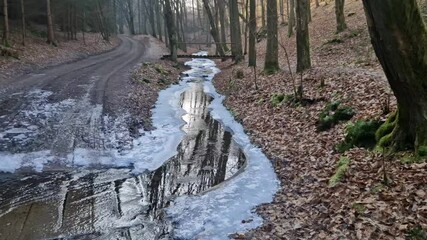 wading through a watercourse on a dirt road in a wooded valley. Ice and snow make the road less passable