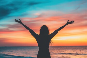 Fototapeta premium Silhouette of woman enjoying vibrant sunset by the ocean