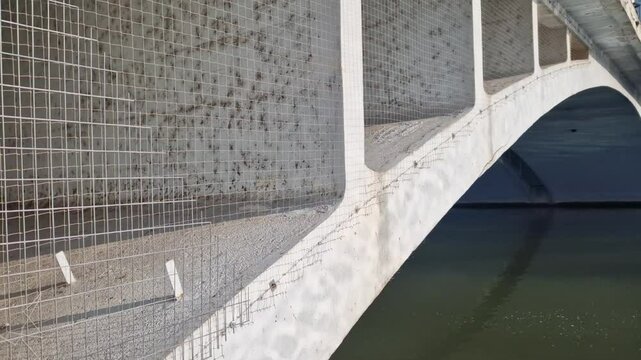 The pillars of the arch bridge are covered with netting to prevent birds from nesting there and damaging the bridge structure with their droppings.