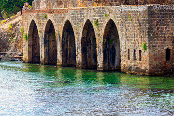 Ancient Alanya shipyard Tersane with stone arches and emerald waters, historical landmark in Turkey...