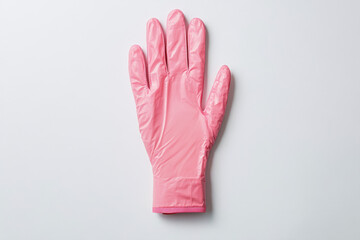 Obraz premium Close-up of a single pink rubber glove against a plain white background, highlighting its texture and vibrant color.