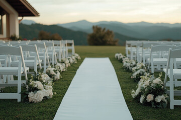 Fototapeta premium White chairs and flowers decorated wedding aisle overlooking mountains