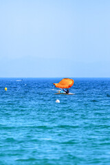 Wing foil athlete falling into the ocean with an orange wing near Tarifa, Spain.