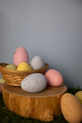 Vertical Easter card with pastel colorful eggs in a twigs basket and wooden piece