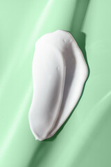 Face or body white cream hair balm or melted wax on  green background