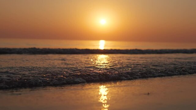 4K Slow motion shot of a beautiful sunset at Mandvi Beach in Kutch, Gujarat, India. Sea waves and entire sea becomes golden in colour during the sunset. Orange colored sea. Natural sea background.