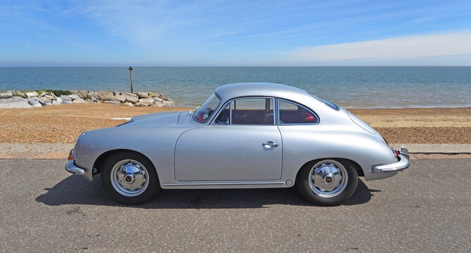 Classic Porsche 356 Coupe automobile parked on seafront  promenade with beach and sea in background.