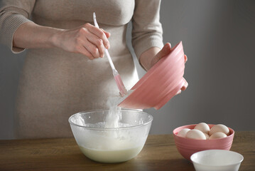 a woman kneads the ingredients for pasta with a spatula with her hands
