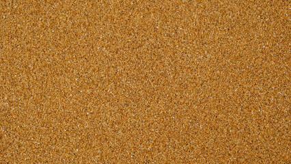 Golden sand background with fine texture of desert or beach. Granules small and tightly packed, uniform and natural pattern. Ideal for yellow textures, summer sun holiday concept or design elements.