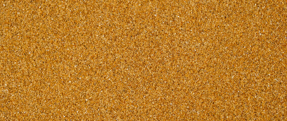 Golden sand background with fine texture of desert or beach. Granules small and tightly packed, uniform and natural pattern. Ideal for yellow textures, summer sun holiday concept or design elements.