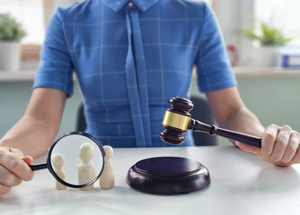 Judicial proceedings with a gavel, magnifying glass, and miniature figures representing people