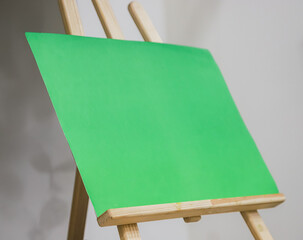 Bright green canvas displayed on a wooden easel in a well-lit indoor studio, perfect for artistic...