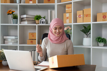 Muslim woman conducting online sales and managing her business from a modern workspace.
