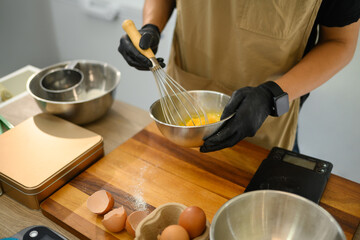 Cropped shot of baker whisking eggs in a stainless steel bowl, preparing cookie dough