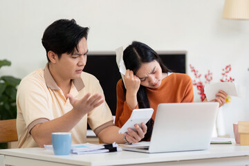 Obraz premium Couple calculating bills and managing finances at home, expressing concern and collaboration.