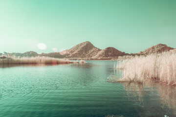 Infrared photography, a calm body of water, surrounded by hills with tall grasses