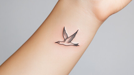 Simple Bird Tattoo: A delicate, minimalist tattoo of a flying bird adorns a wrist, showcasing the elegance and freedom of a simple yet powerful design.  